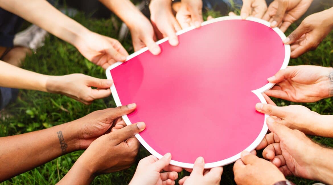 a group of hands holding a heart shaped sign